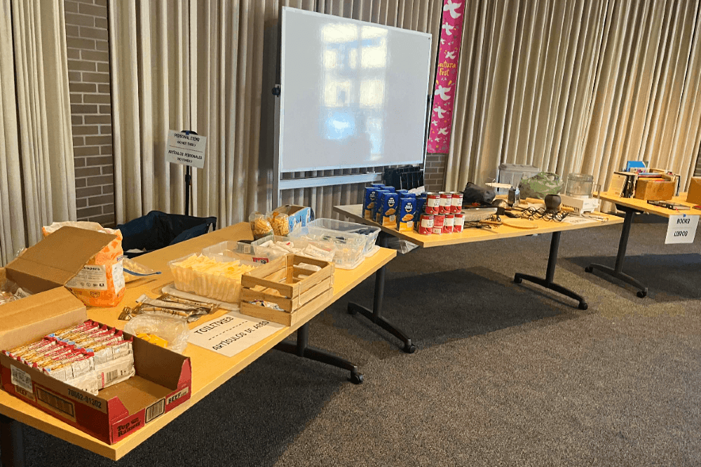 Several tables full of food and goods for distribution in the Santa Rosa Central Library meeting room.